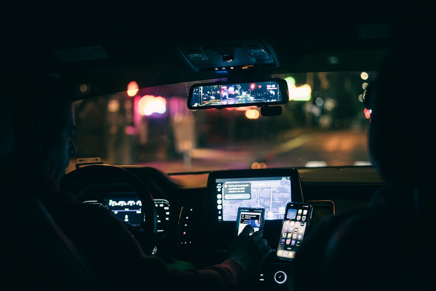 Motorista ao volante utilizando o aplicativo de navegação durante uma corrida noturna na cidade